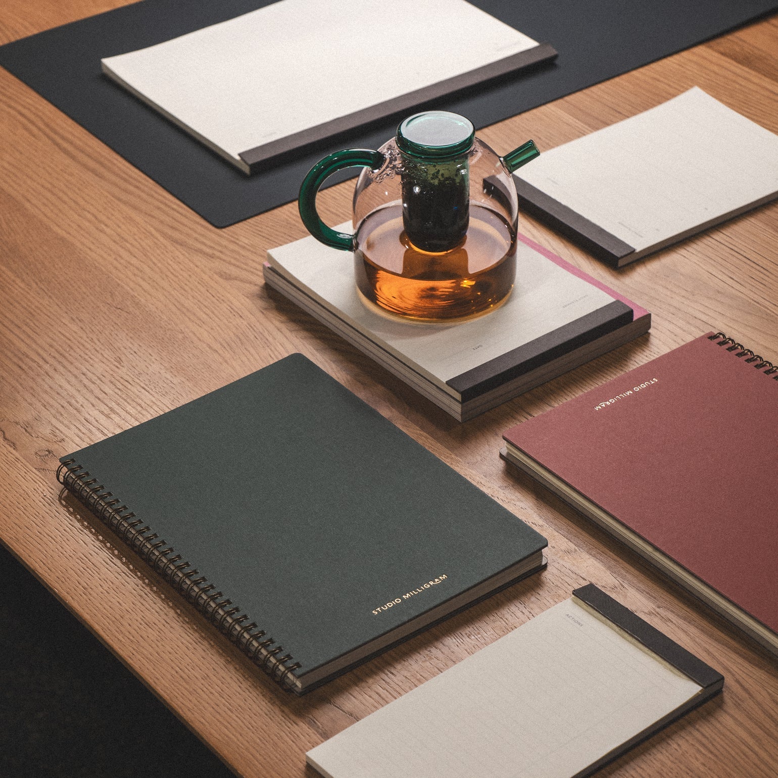 Collection of notebooks and a teapot on a wooden surface