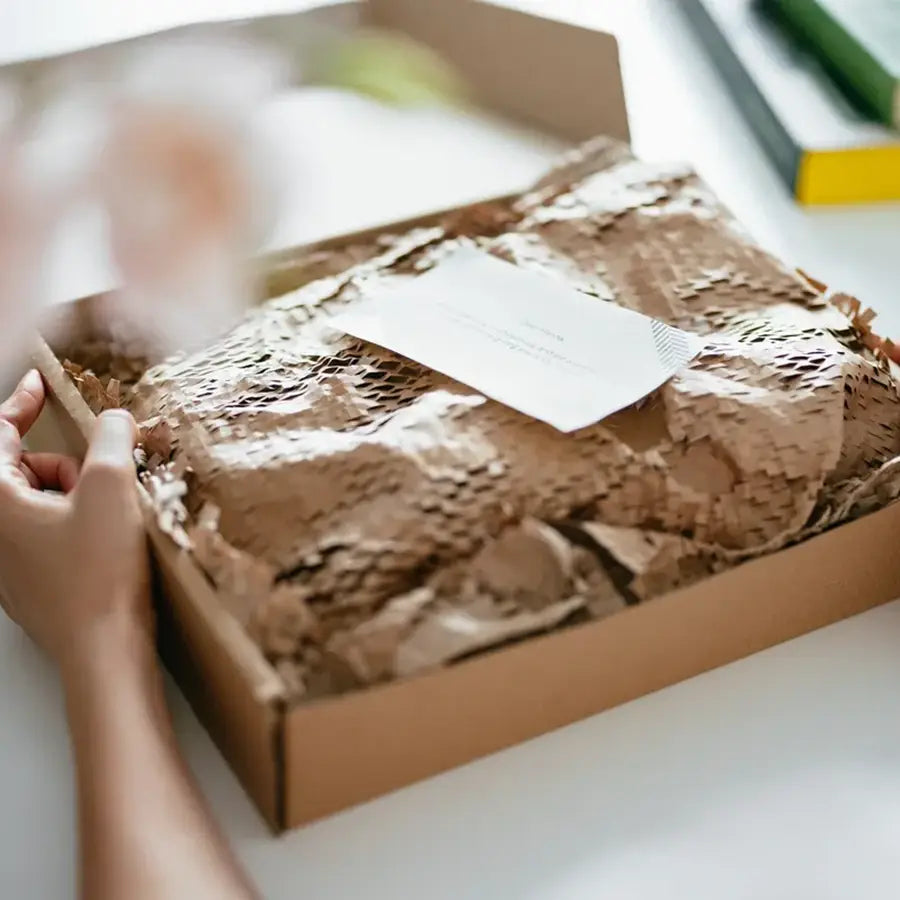 Person opening a box with brown textured paper and a white label.